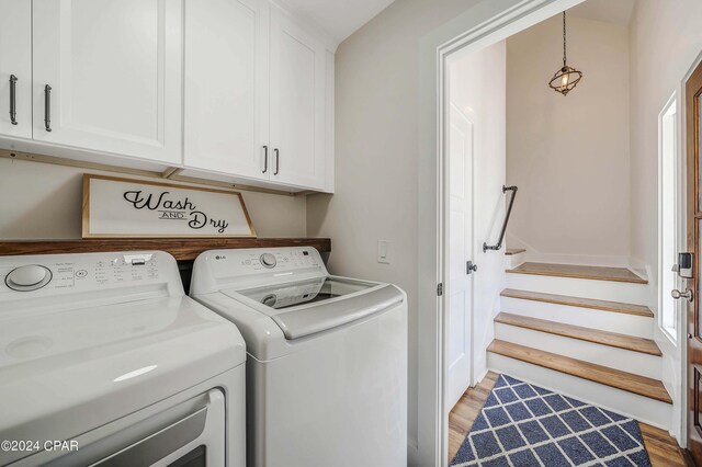 laundry area with cabinets, wood-type flooring, and washing machine and clothes dryer