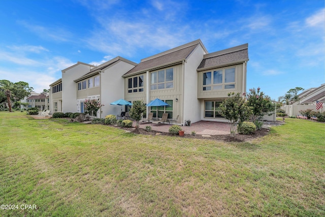 rear view of property featuring a patio and a lawn