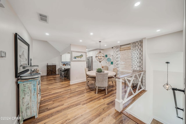 dining area with an inviting chandelier and light hardwood / wood-style flooring