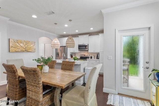 dining area with sink, dark wood-type flooring, and crown molding