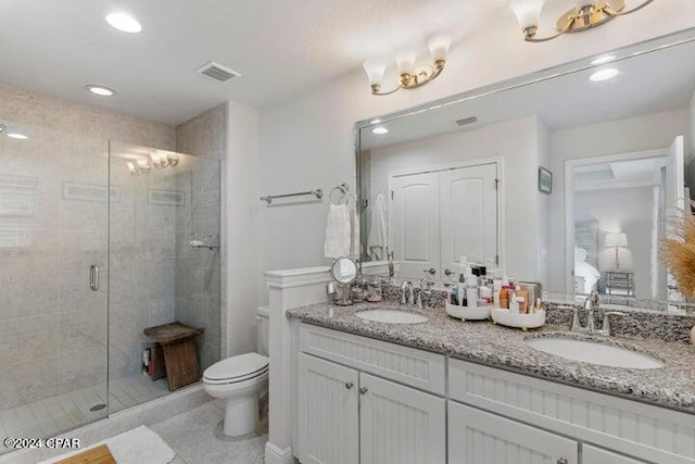 bathroom featuring double vanity, toilet, a stall shower, and a sink