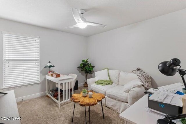 office space featuring baseboards, light carpet, and a ceiling fan