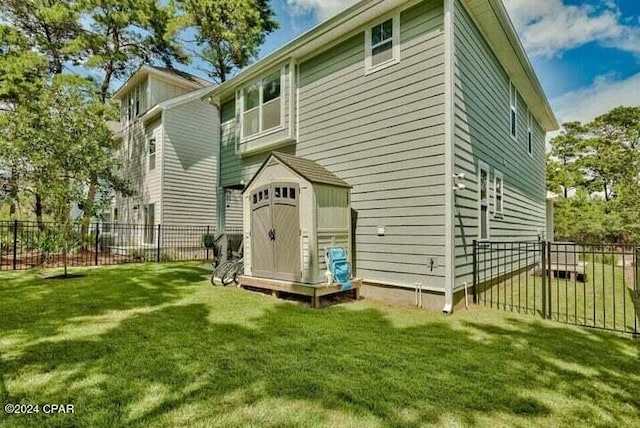 back of house featuring a storage unit, a yard, an outdoor structure, and fence