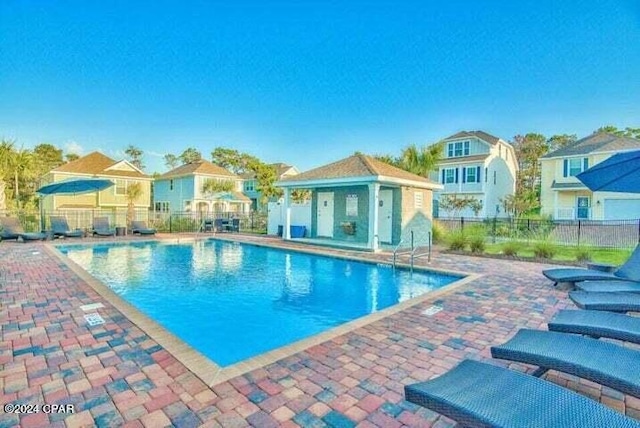 pool featuring a patio, fence, and a residential view