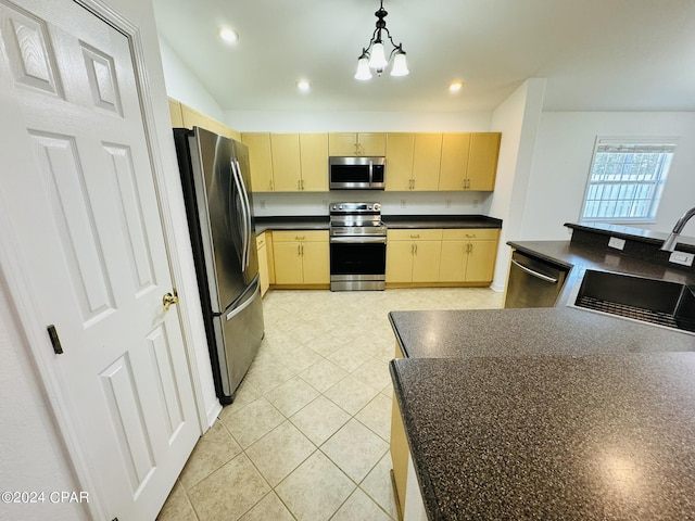 kitchen featuring light brown cabinets, stainless steel appliances, a sink, dark countertops, and pendant lighting