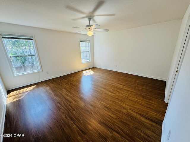 empty room with wood finished floors, a ceiling fan, and baseboards