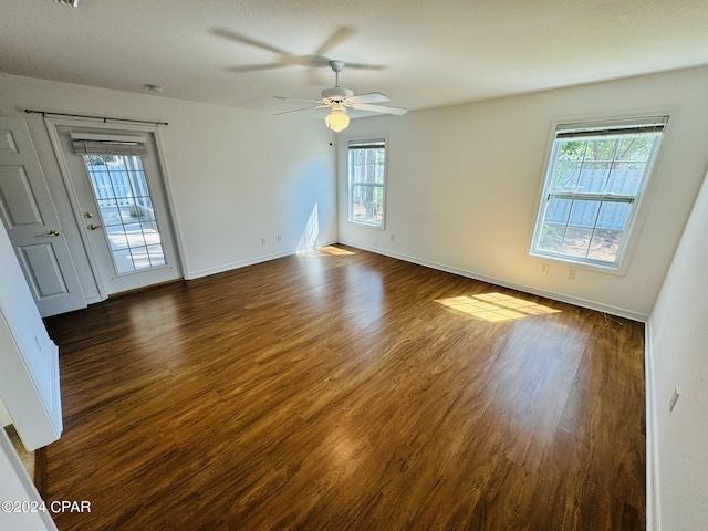 unfurnished room with ceiling fan, dark wood-style flooring, and baseboards