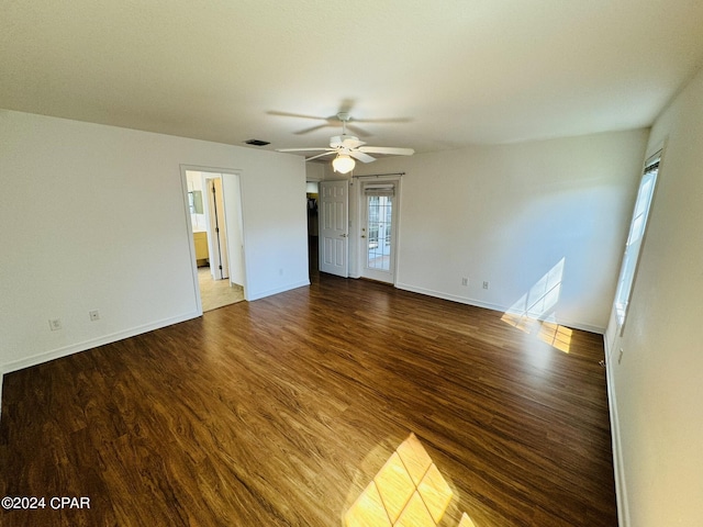 unfurnished room with a ceiling fan, wood finished floors, visible vents, and baseboards