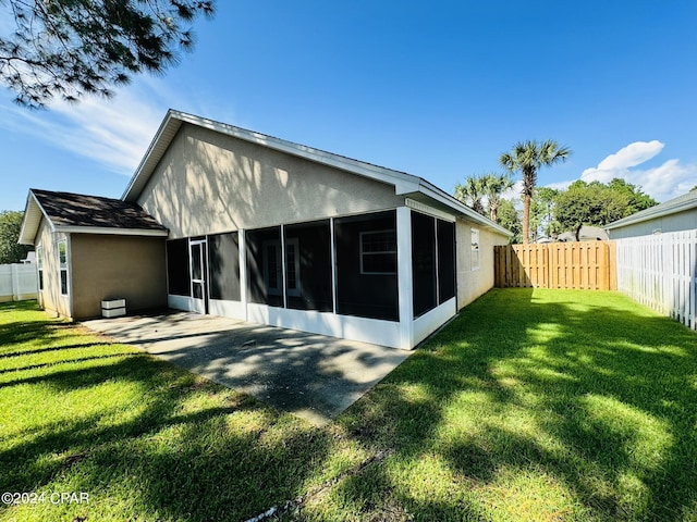 rear view of house with a sunroom, a fenced backyard, and a lawn