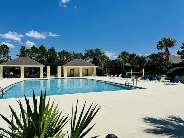 community pool with a patio area, fence, and a gazebo