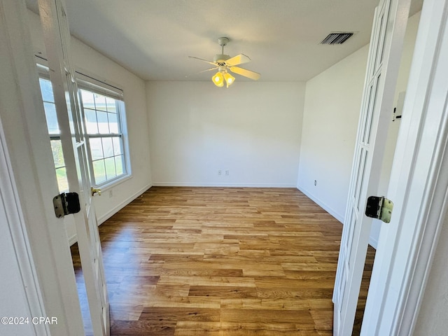 spare room featuring baseboards, light wood-type flooring, visible vents, and a ceiling fan