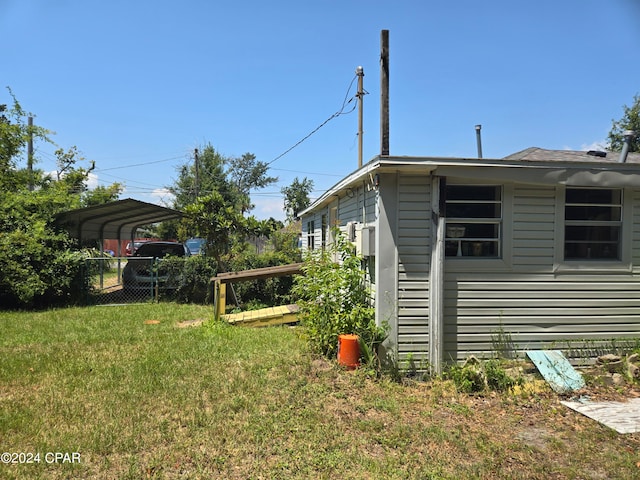 view of side of property featuring a lawn and a carport