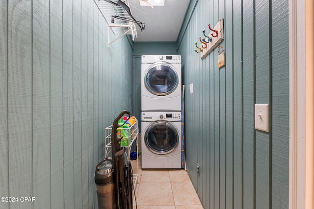 washroom with wooden walls, stacked washing maching and dryer, and light tile patterned floors