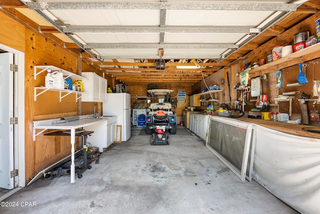 garage with a workshop area, white refrigerator, and sink