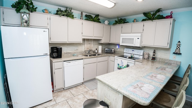 kitchen with crown molding, white appliances, kitchen peninsula, and a kitchen breakfast bar