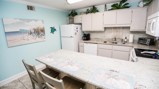 kitchen with white appliances, a breakfast bar, kitchen peninsula, ornamental molding, and sink