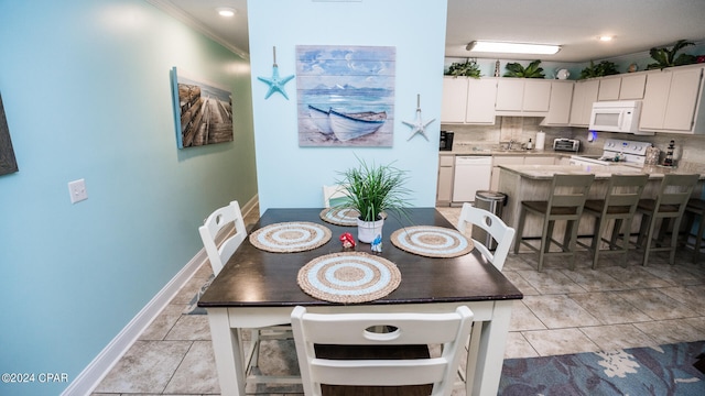 tiled dining room featuring crown molding and sink