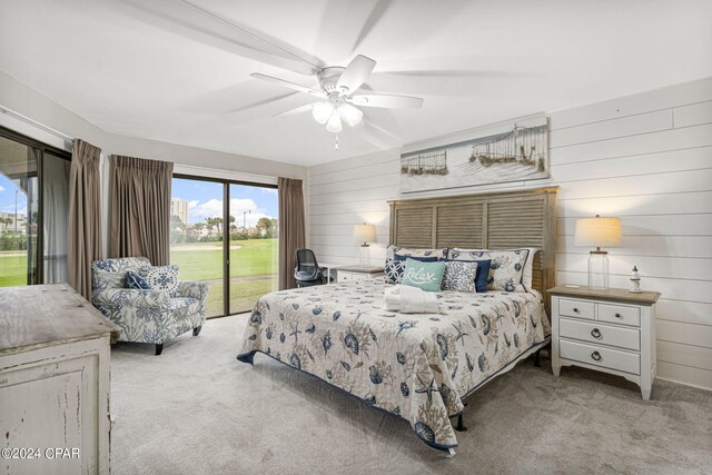 bedroom with ceiling fan, wooden walls, light colored carpet, and access to outside