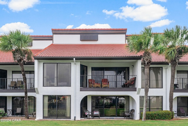 back of house with a balcony and a yard