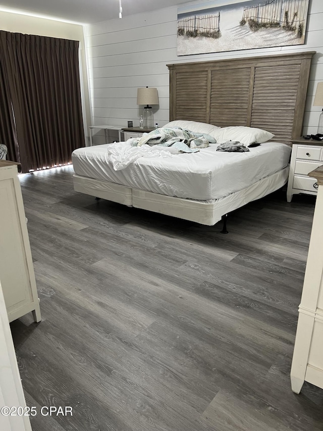 bedroom with dark wood-type flooring and wood walls