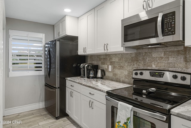 kitchen with light stone counters, tasteful backsplash, stainless steel appliances, and white cabinets