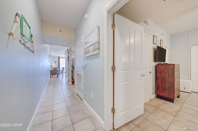 corridor featuring light tile patterned floors and baseboards