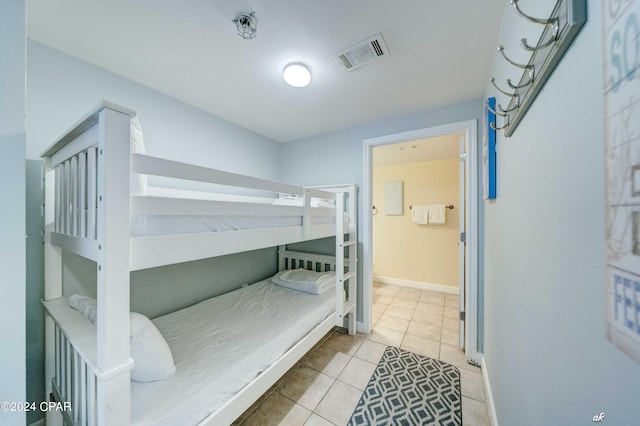 tiled bedroom featuring visible vents, baseboards, and ensuite bathroom