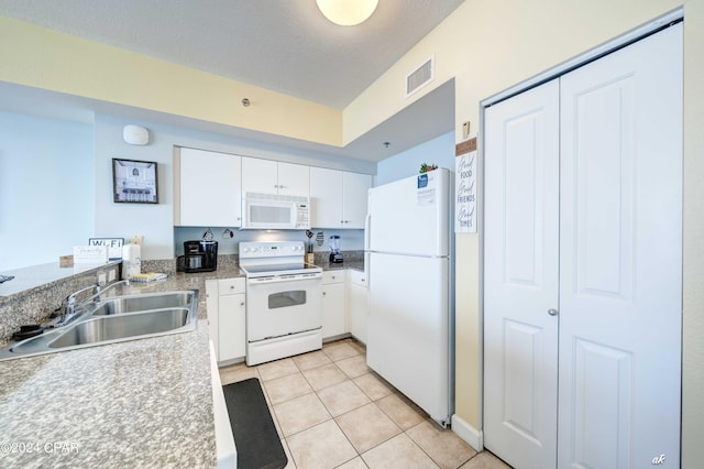 kitchen featuring white appliances, light tile patterned floors, white cabinets, visible vents, and a sink