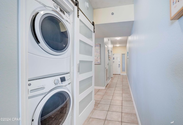 washroom with a barn door, light tile patterned floors, and stacked washing maching and dryer