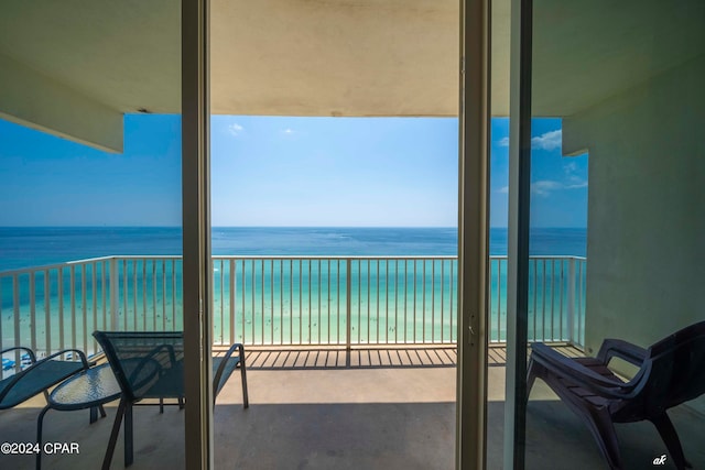 balcony with a water view and a view of the beach