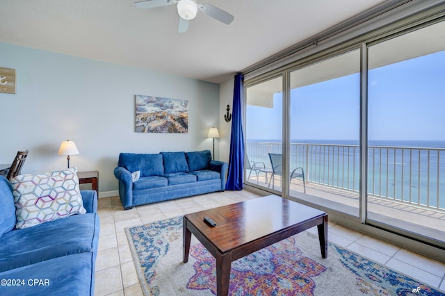 living area featuring light tile patterned floors, baseboards, a ceiling fan, and a water view