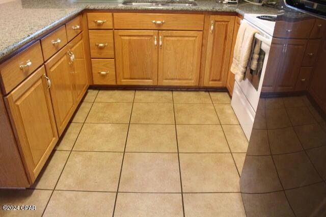 kitchen featuring light tile patterned floors, light stone countertops, and sink