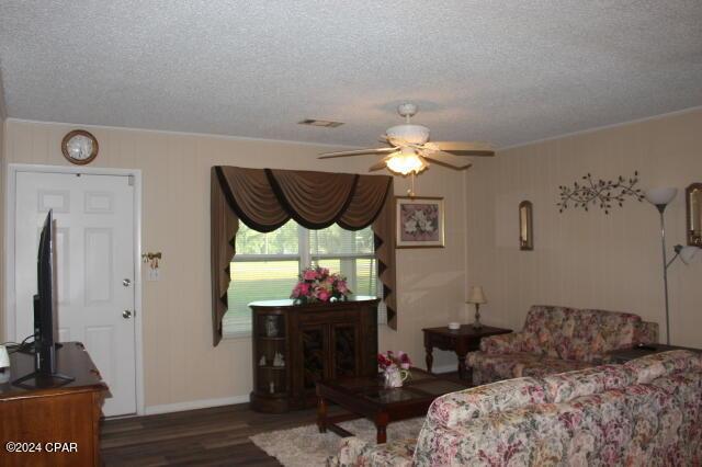 living room featuring ceiling fan, a textured ceiling, and dark hardwood / wood-style flooring