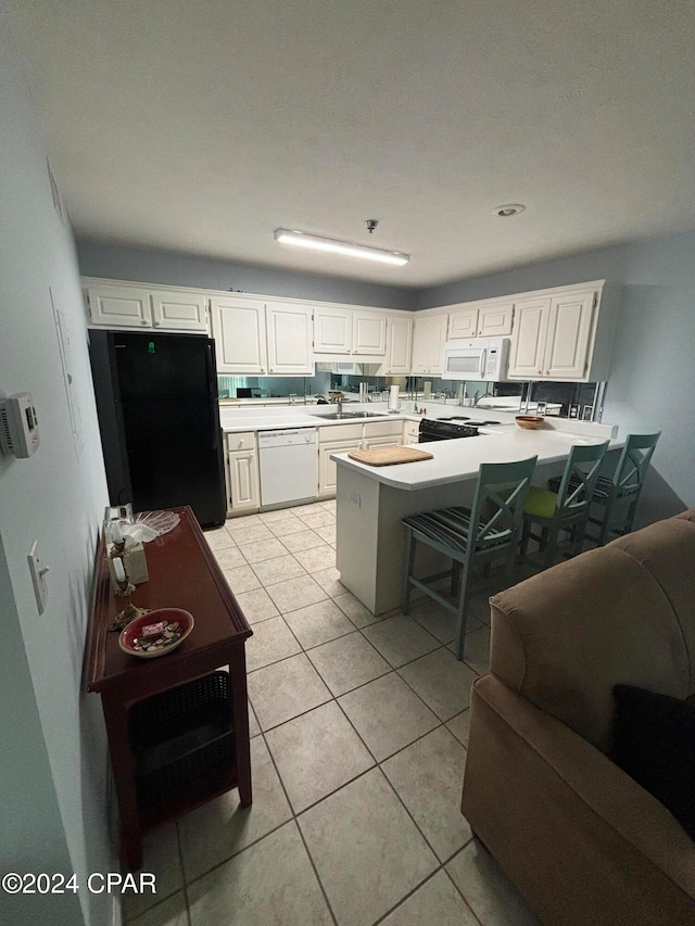 kitchen with white cabinets, white appliances, a kitchen bar, and sink