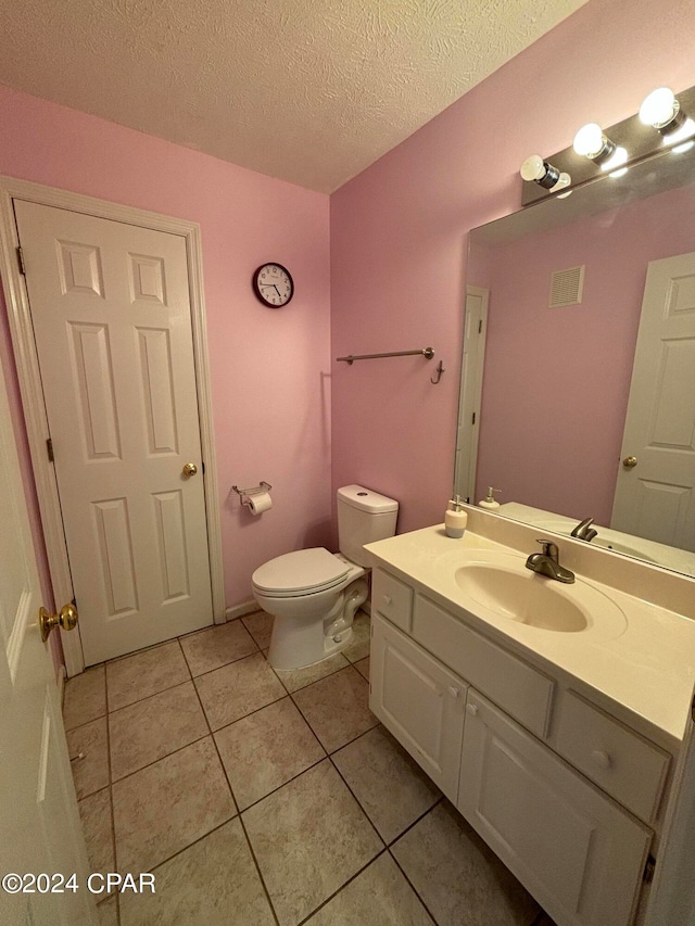 bathroom featuring vanity, toilet, a textured ceiling, and tile patterned floors