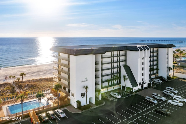 view of property with a community pool, a beach view, and a water view