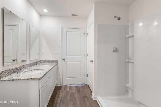 bathroom featuring walk in shower, vanity, hardwood / wood-style floors, and a textured ceiling