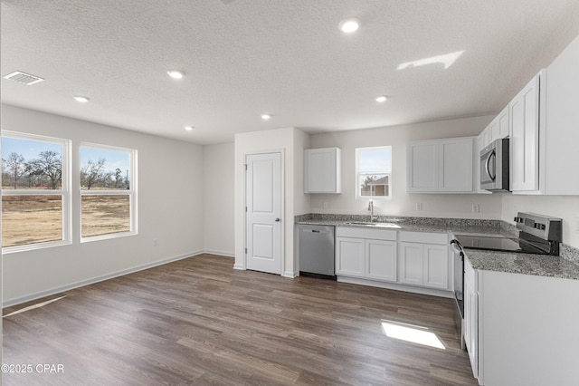 kitchen featuring appliances with stainless steel finishes, sink, white cabinets, and dark hardwood / wood-style flooring