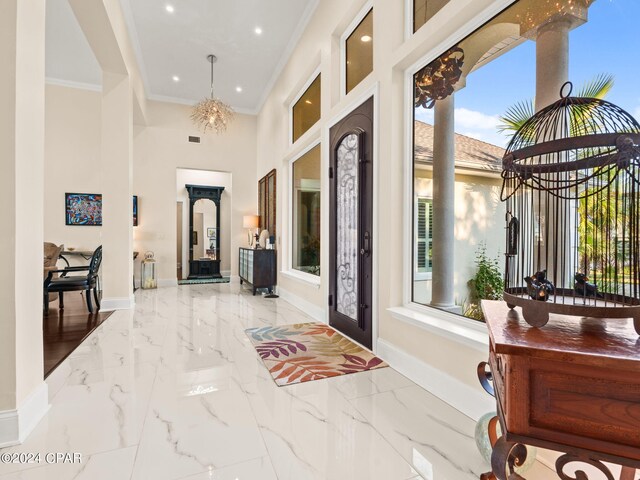 hallway with light tile patterned floors, a high ceiling, a chandelier, and ornamental molding