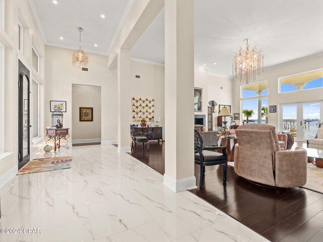 foyer entrance with hardwood / wood-style floors, french doors, a high ceiling, crown molding, and a notable chandelier