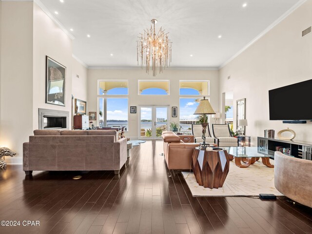 living room with a high ceiling, ornamental molding, dark hardwood / wood-style flooring, and a chandelier