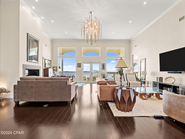 living room with a towering ceiling, a glass covered fireplace, and dark wood finished floors