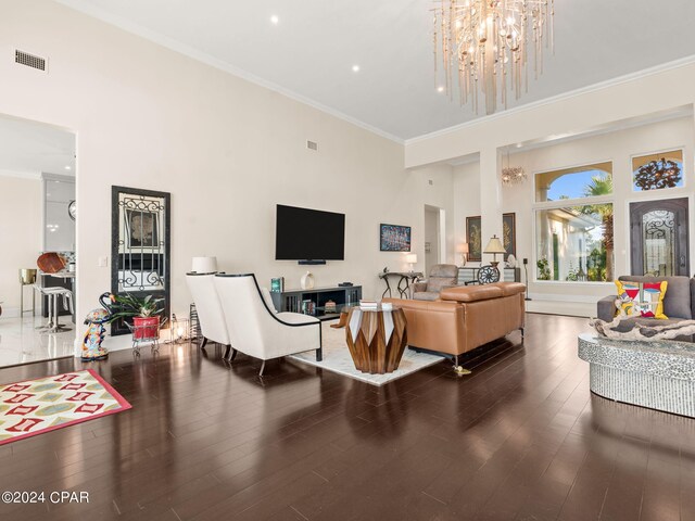 living room with a high ceiling, crown molding, wood-type flooring, and a chandelier