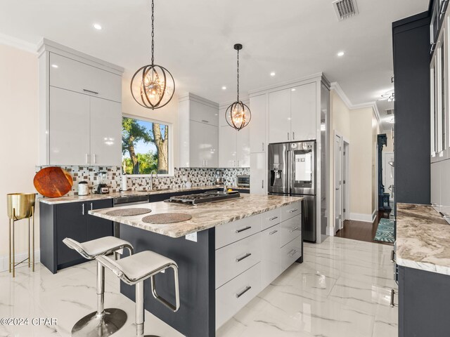 kitchen with decorative backsplash, light hardwood / wood-style flooring, a kitchen island, hanging light fixtures, and crown molding