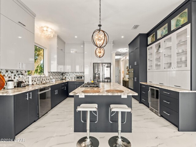 kitchen featuring light tile patterned flooring, a center island, light stone counters, white cabinetry, and stainless steel appliances