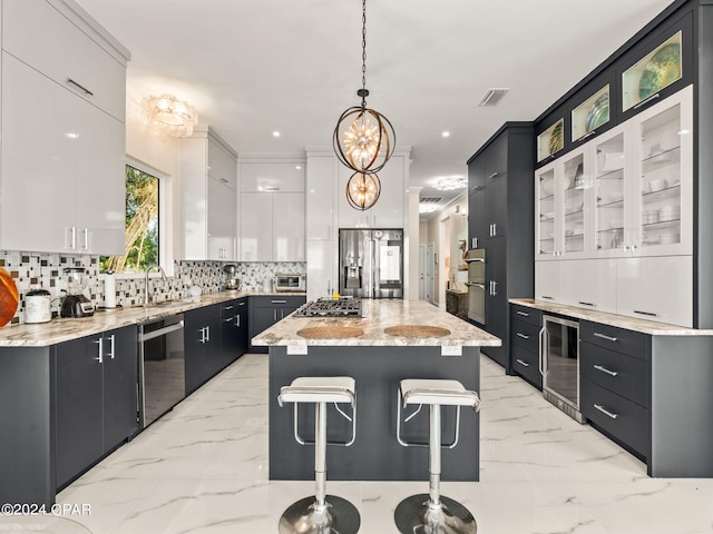 kitchen with decorative light fixtures, stainless steel appliances, marble finish floor, a center island, and glass insert cabinets