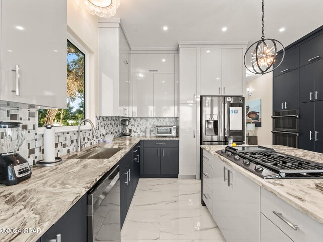 kitchen with backsplash, sink, decorative light fixtures, appliances with stainless steel finishes, and white cabinetry