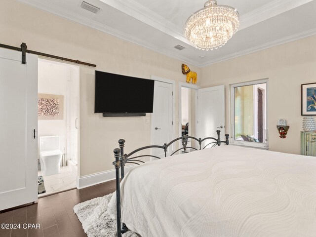 bedroom featuring a barn door, ornamental molding, hardwood / wood-style flooring, a notable chandelier, and connected bathroom