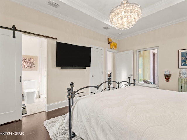 bedroom with a barn door, visible vents, dark wood finished floors, ornamental molding, and a tray ceiling