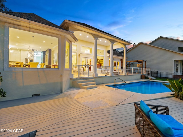 pool at dusk with a patio area, fence, and a fenced in pool